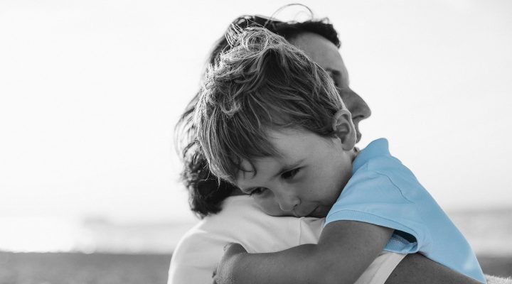 Mother comforts her son as he rests on her shoulder