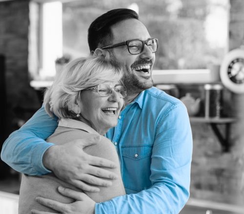 Adult son gives his mother a warm hug in his childhood home