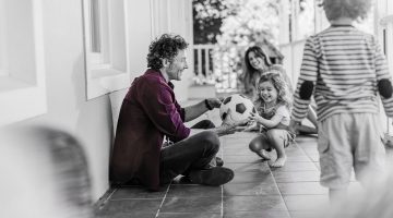 A young father receives a soccer ball as he plays with his young daughter, her mother and brother looking on gleefully