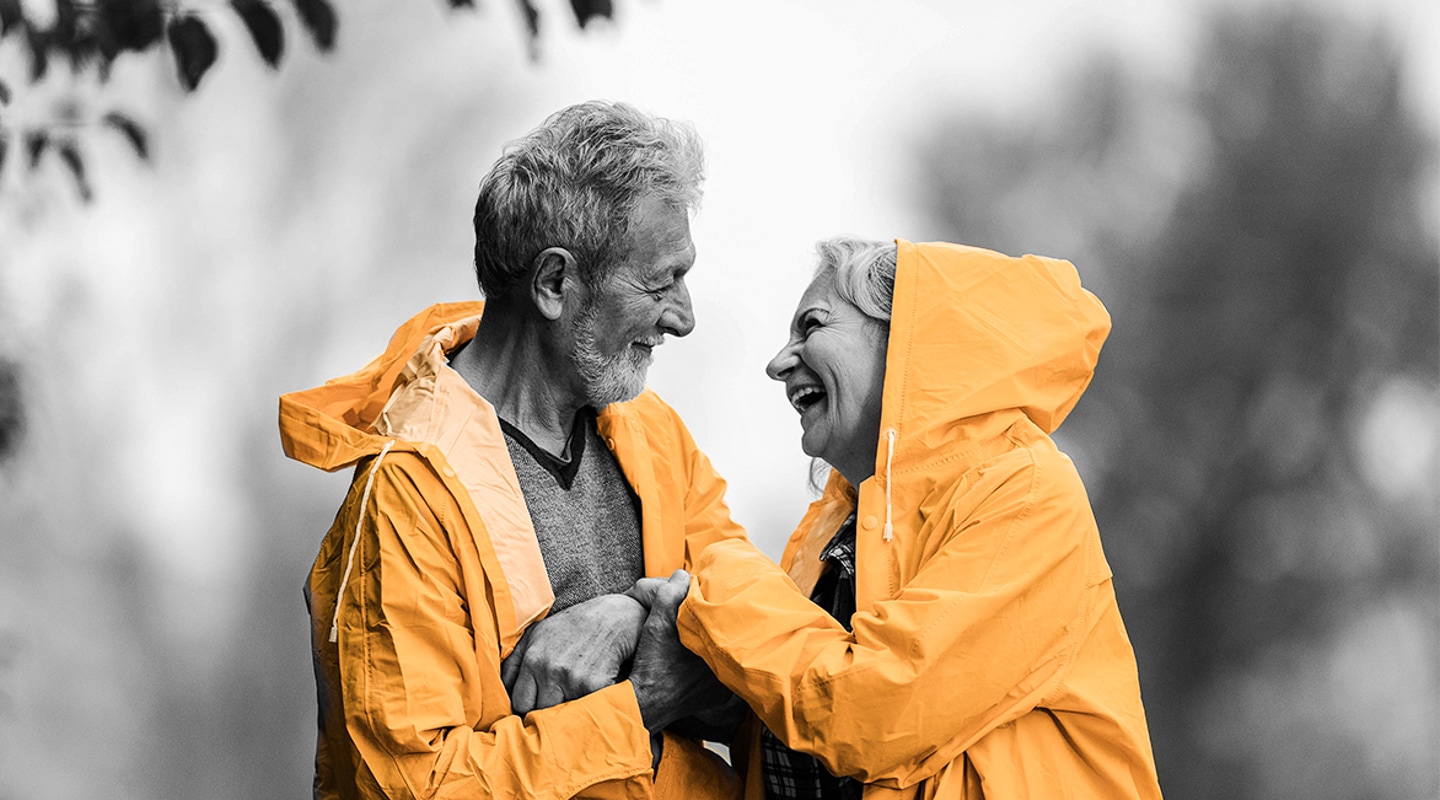 A retired husband and wife share a playful embrace in the rain