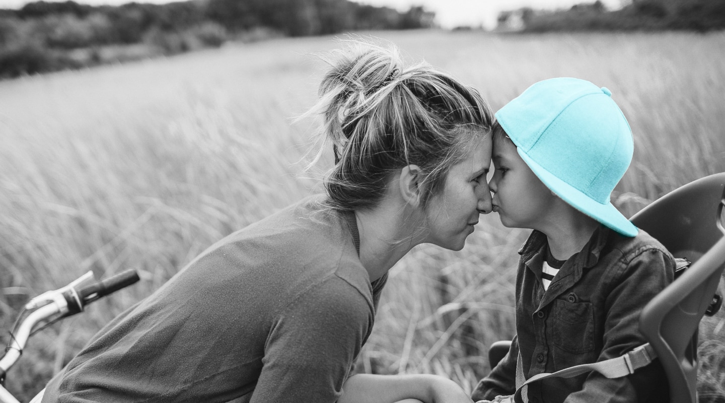 Mother and son share a tender nose touch in an open field